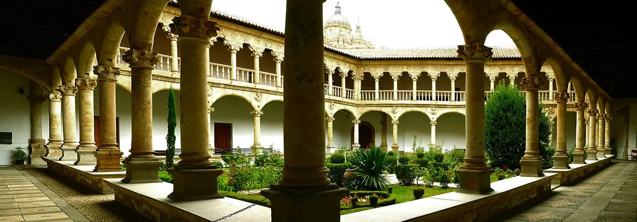 Vista panorámica del claustro desde la galería baja, con el jardín y la cúpula de la Catedral al fondo